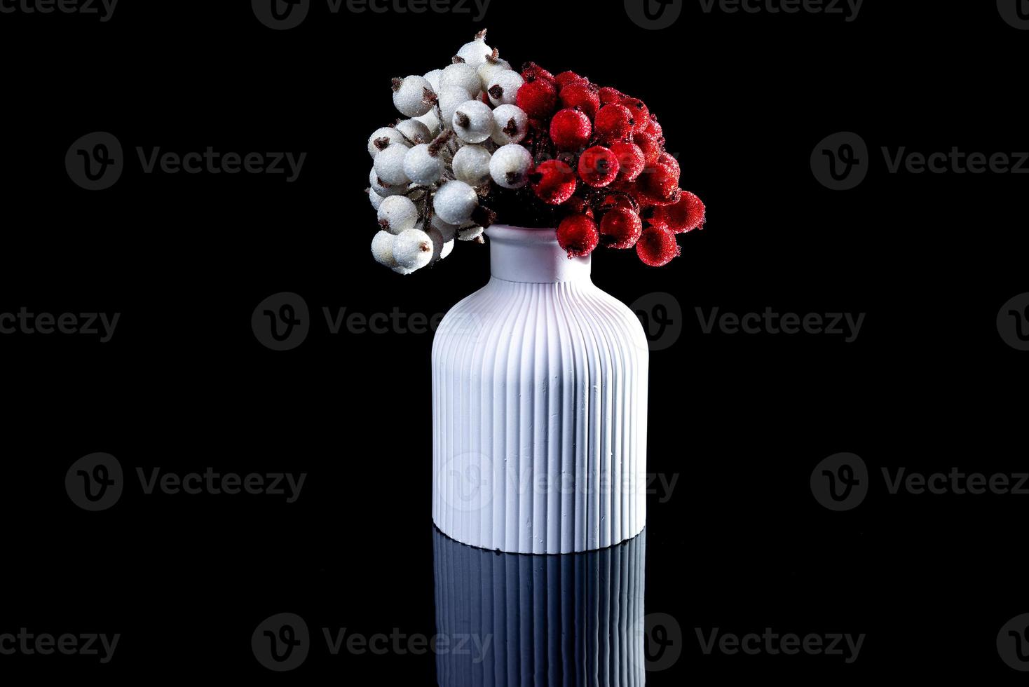 white vase with white and red berries in ice with reflection, black background isolated, photo