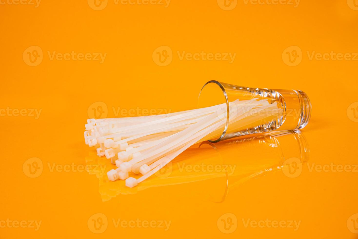 nylon cable ties in glass in jar in bucket on orange background photo
