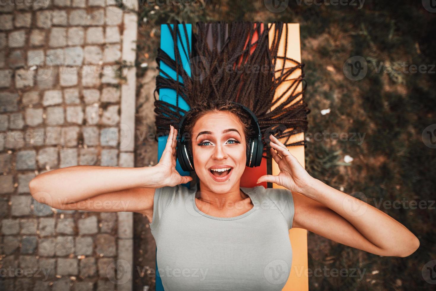 mujer con largas trenzas afro escuchando música desde unos auriculares al aire libre foto