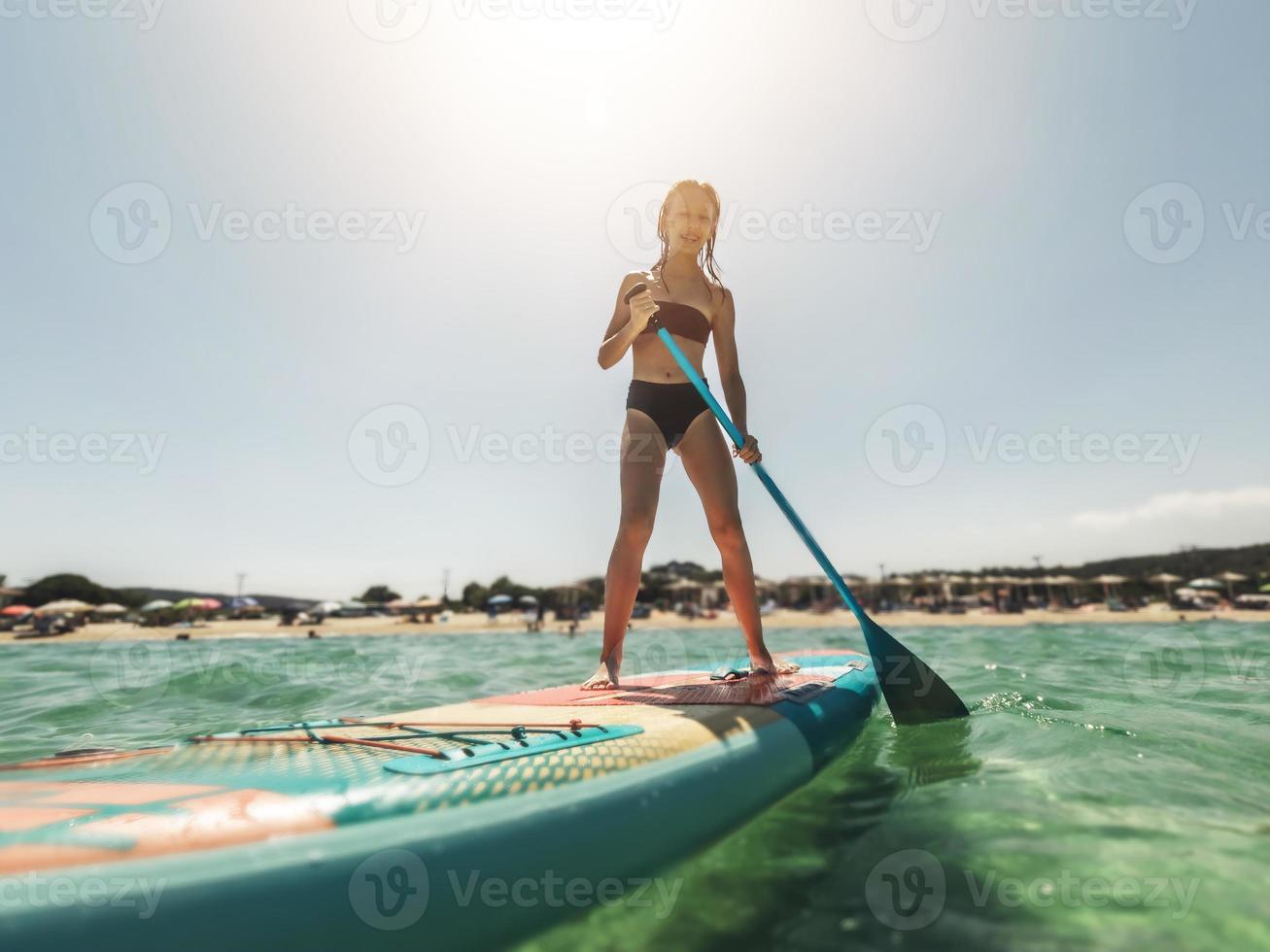 Teeen Girl Paddling On SUP or Stand Up Paddle Board In The Sea photo