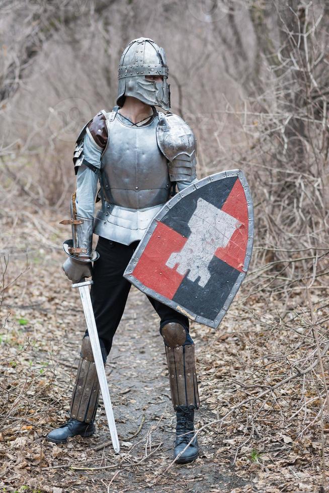 Noble warrior. Portrait of one medeival warrior or knight in armor and helmet with shield and sword posing photo