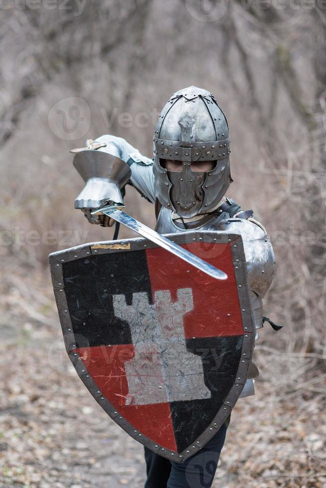 noble guerrero. retrato de un guerrero medieval o caballero con armadura y casco con escudo y espada posando foto