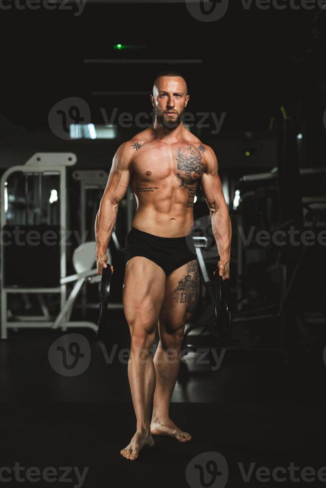 Man Exercise With Weights And Showing His Muscles At The Gym photo