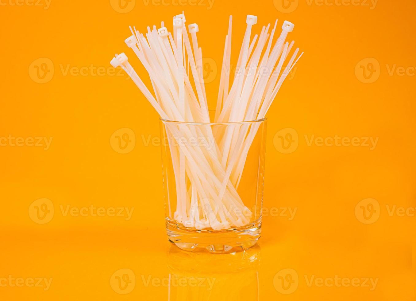 nylon cable ties in glass in jar in bucket on orange background photo