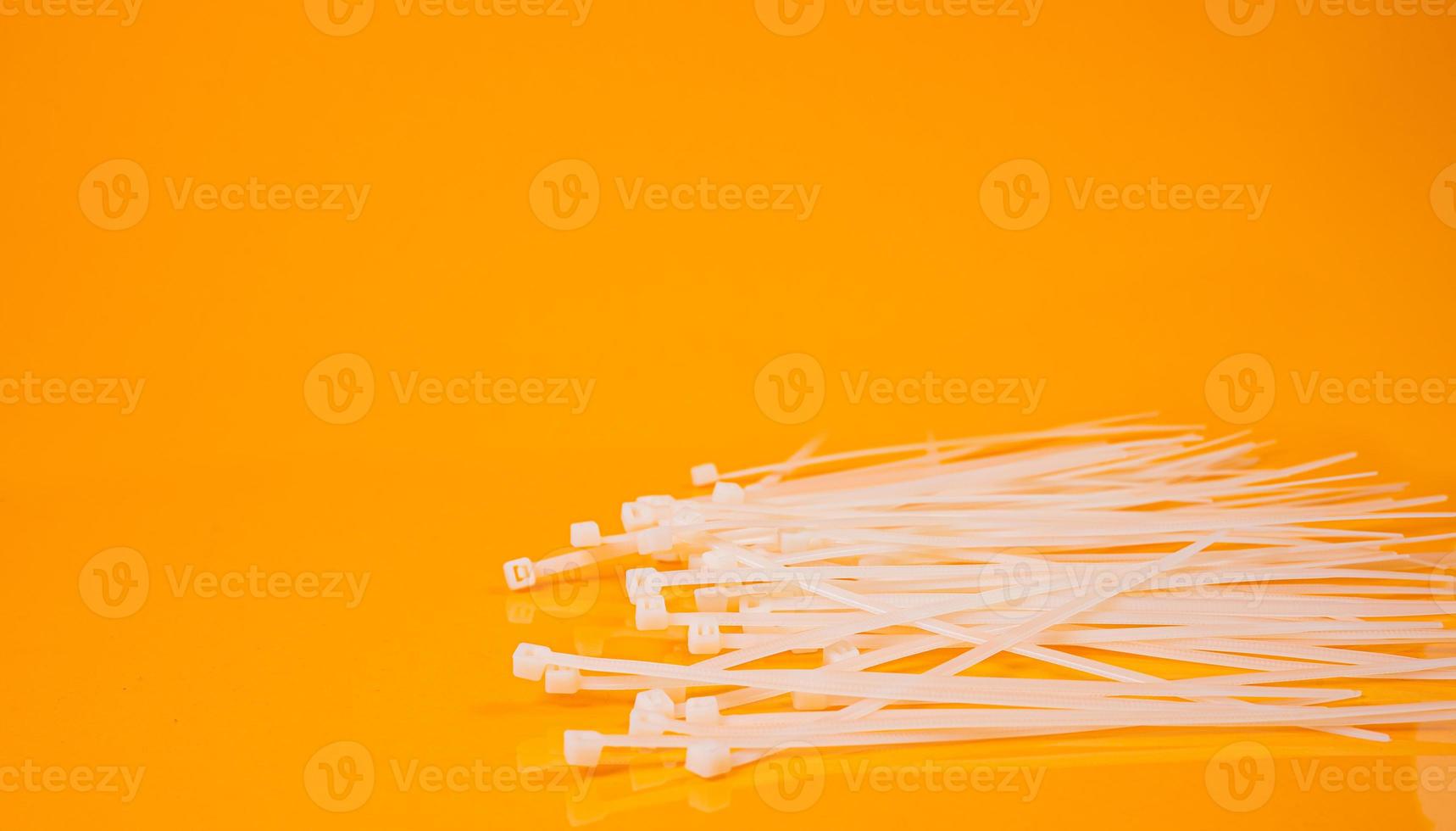 nylon cable ties in glass in jar in bucket on orange background photo