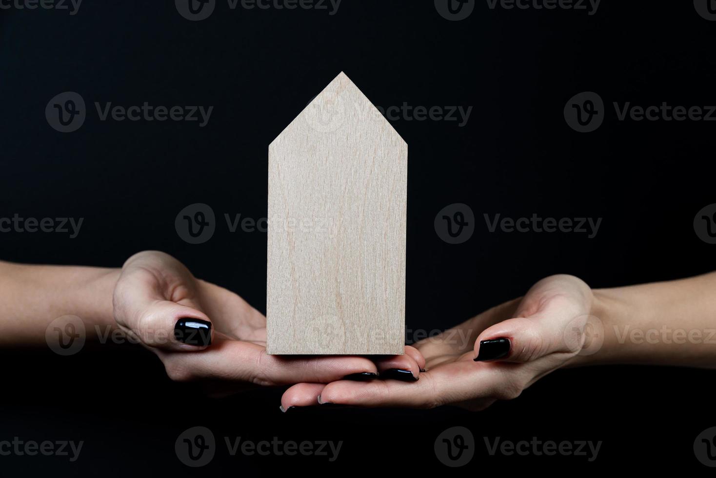 Houses symbol Hand with metal key on black background. Real estate, insurance concept, mortgage, buy sell house, realtor concept, little cars, trees photo