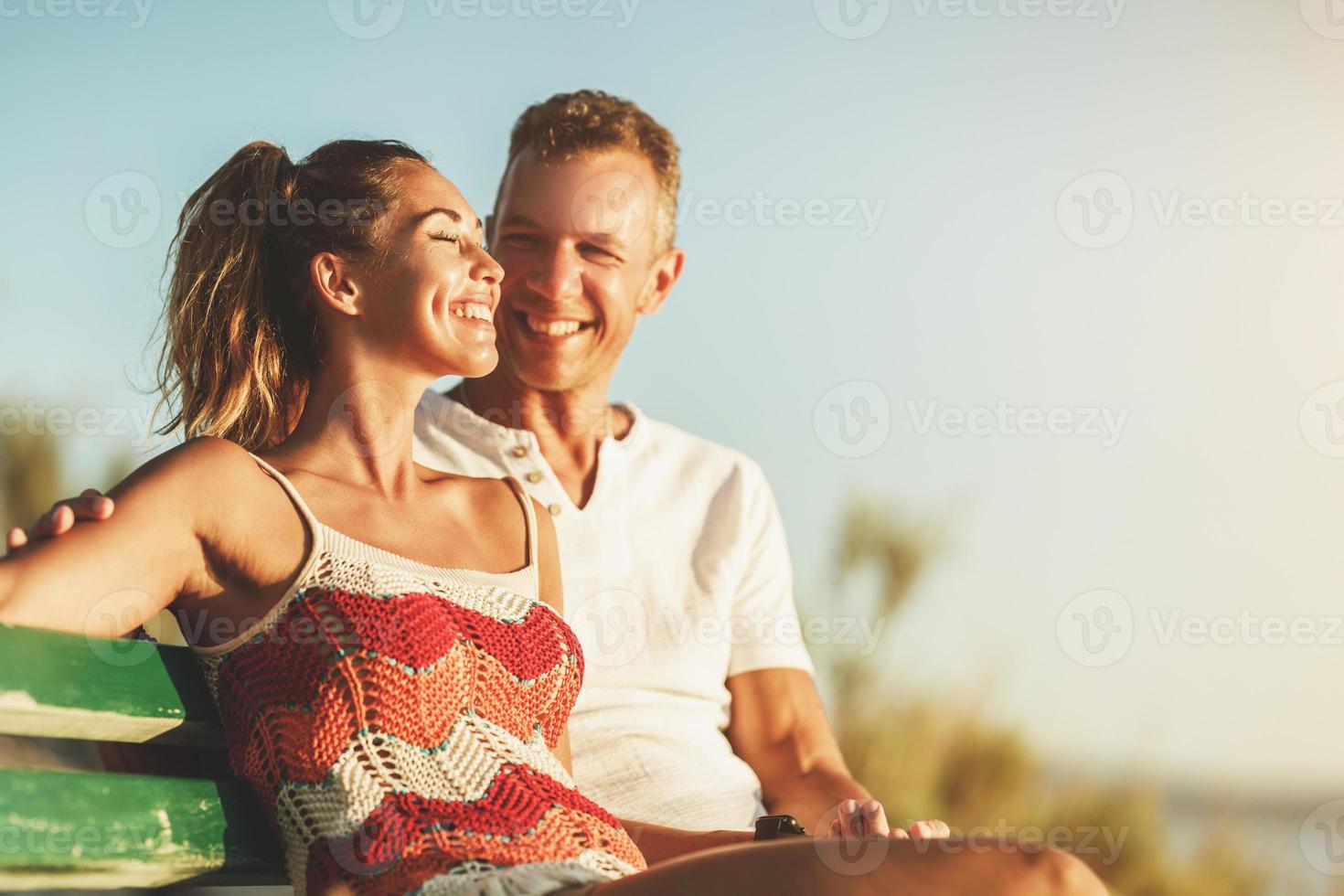 Couple Sitting On Bench And Enjoying Time On A Vacation Near The Beach photo