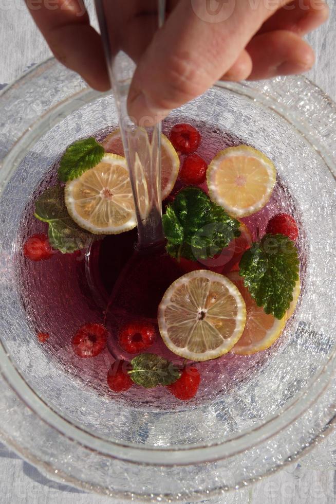 bebida roja saludable con rodajas de cítricos y bayas en el recipiente de vidrio con el cucharón. foto