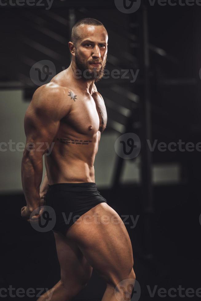 hombre fitness mostrando sus músculos en el gimnasio foto