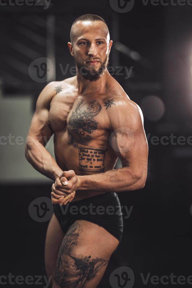 hombre fitness mostrando sus músculos en el gimnasio foto