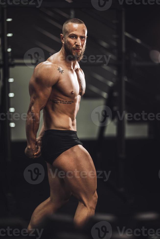 hombre fitness mostrando sus músculos en el gimnasio foto