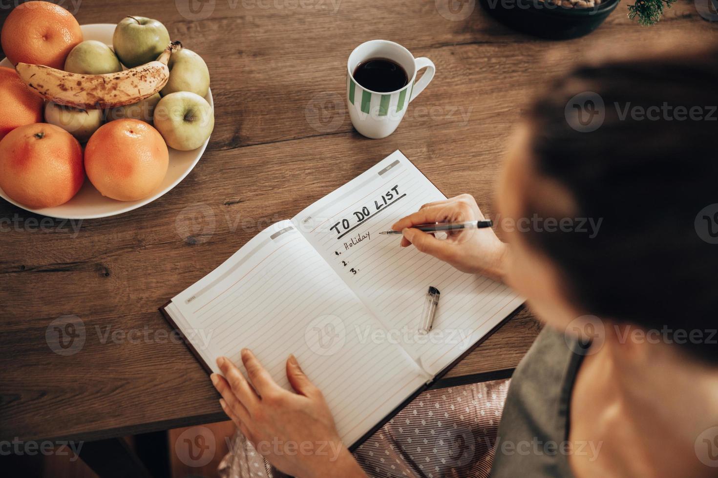 Woman Making To Do List While Enjoying Morning Coffee At Home photo
