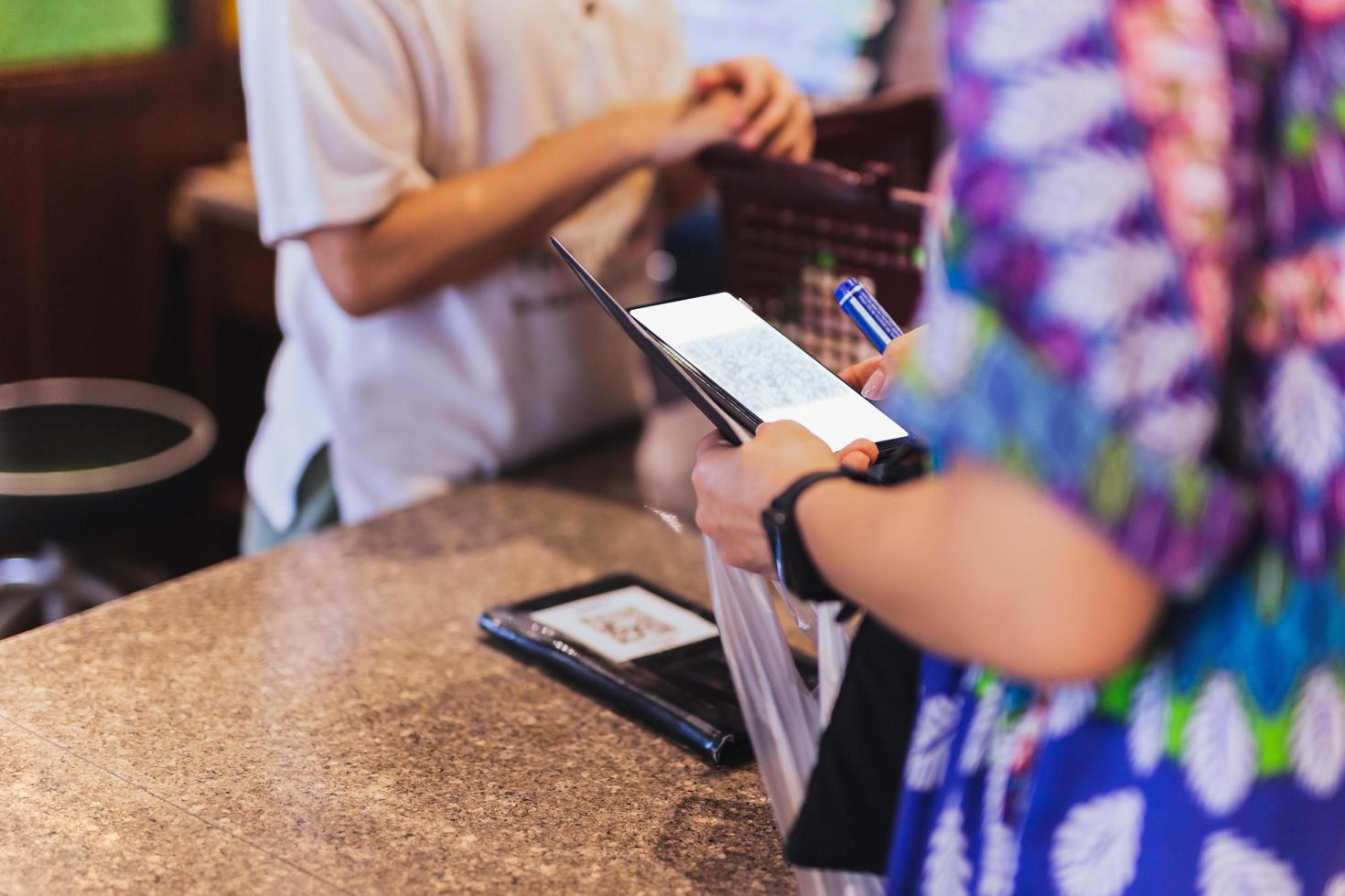 Woman customer scanning QR code payment via mobile phone at cashier counter in store. photo