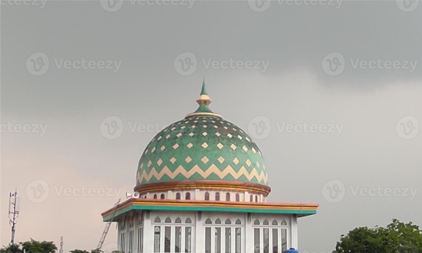 The dome of the mosque is shrouded in overcast clouds. Simple photo about mosque and cloudy. Religious photo for the design of the celebration of religious activities