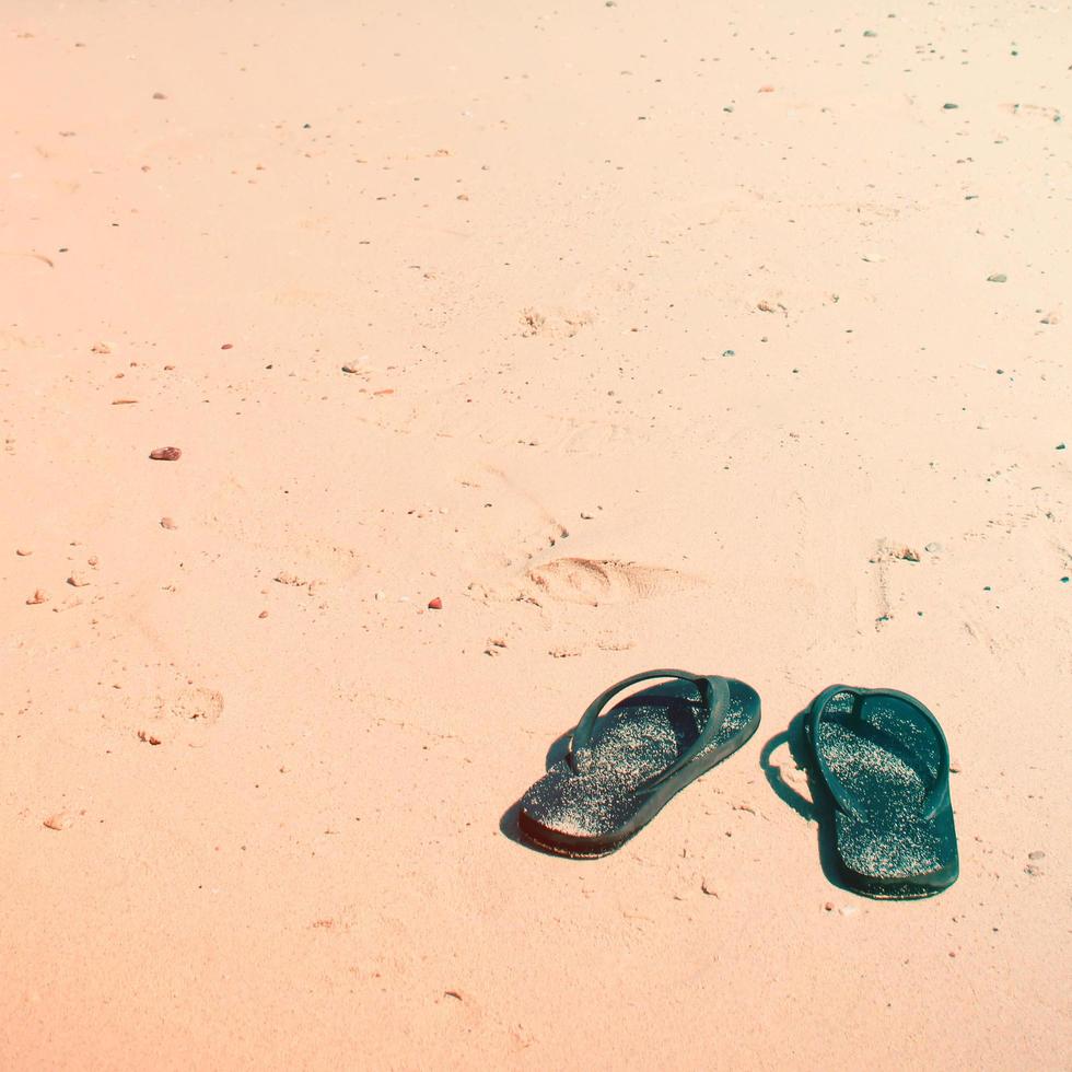 Flip flops on a sandy ocean beach with retro filter style photo