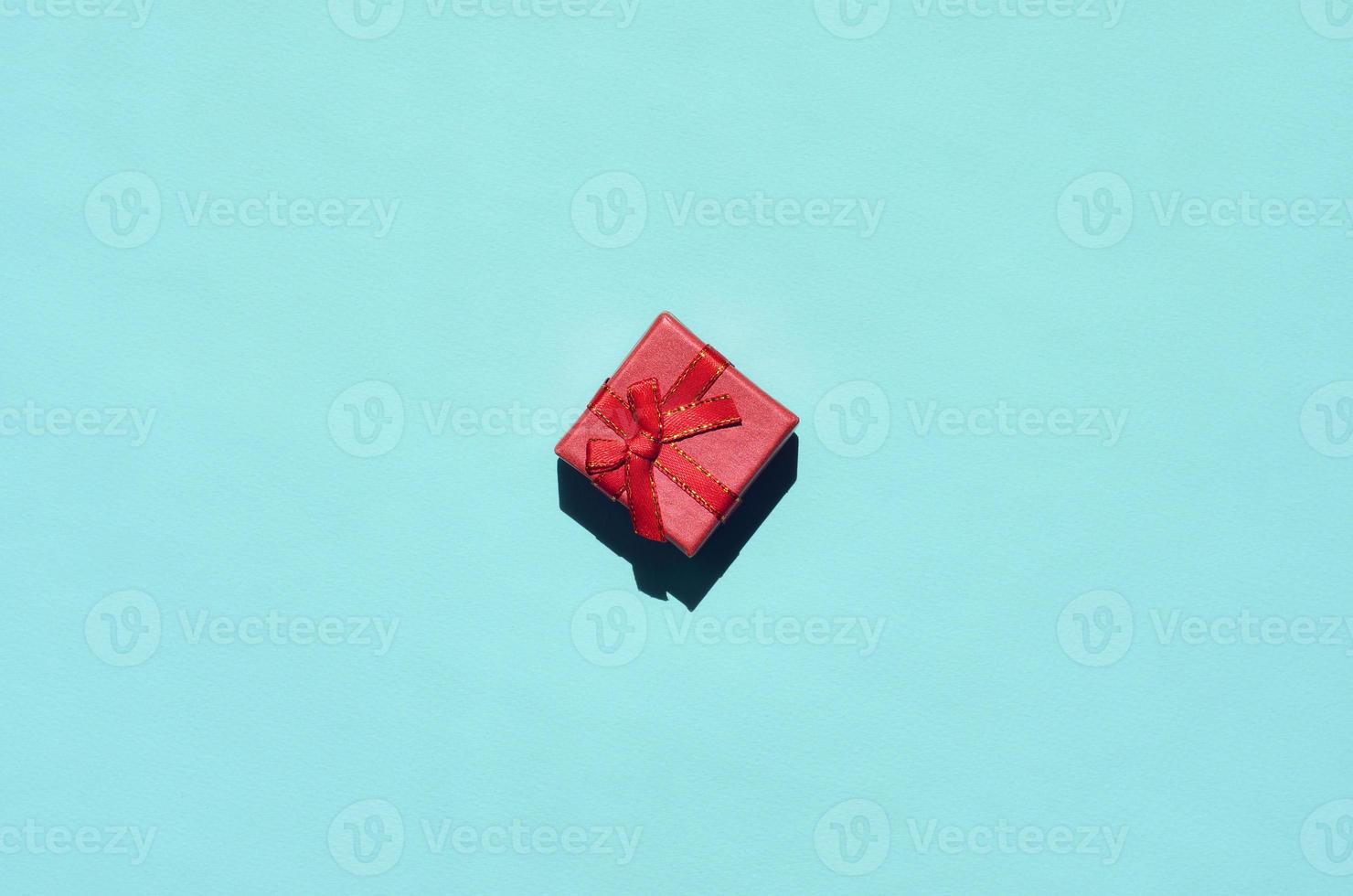 Small red pink gift box lie on texture background of fashion trendy pastel blue color paper in minimal concept photo