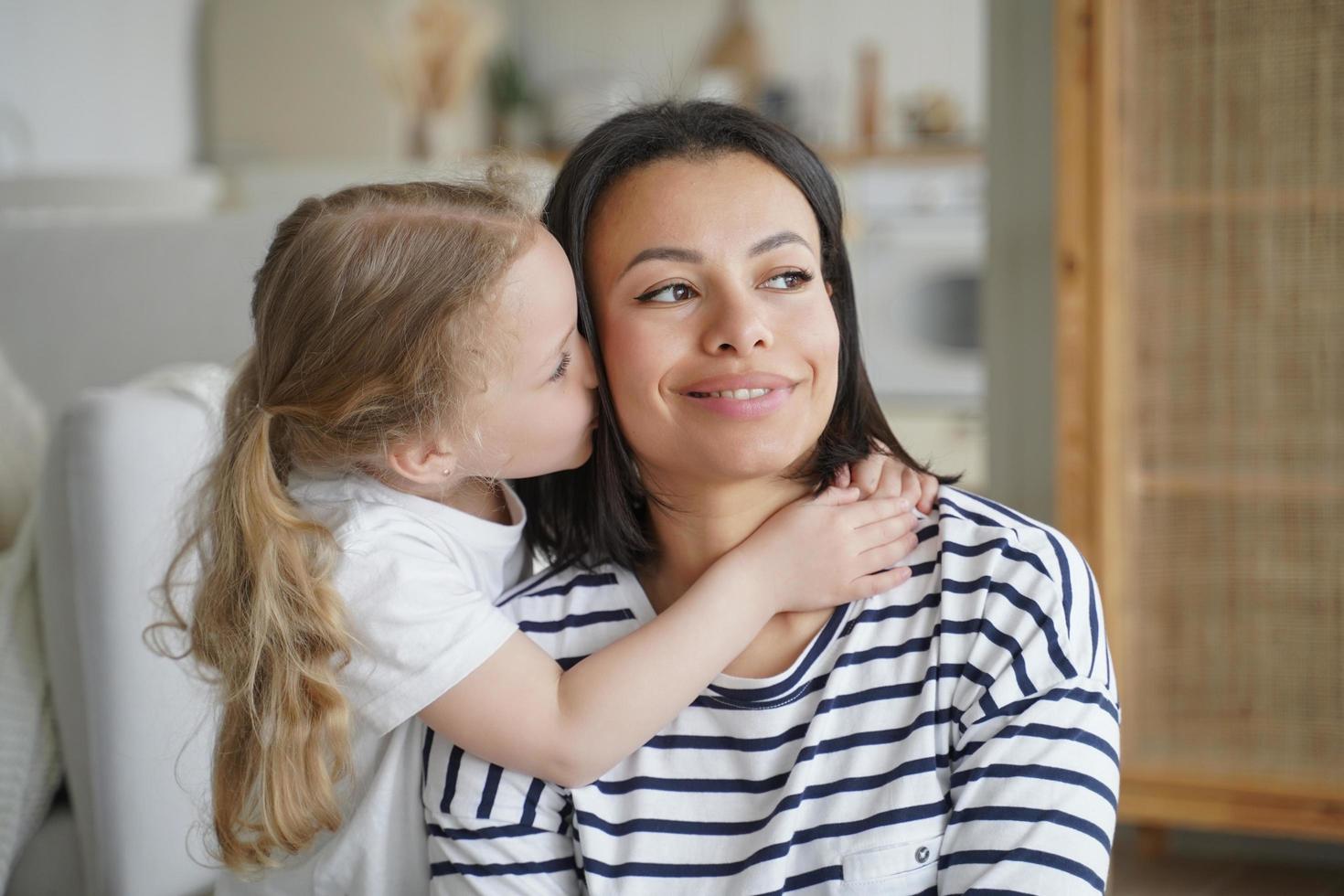 Loving adopted daughter hugs, kissing foster mom. Happy motherhood, custody of child girl, adoption photo