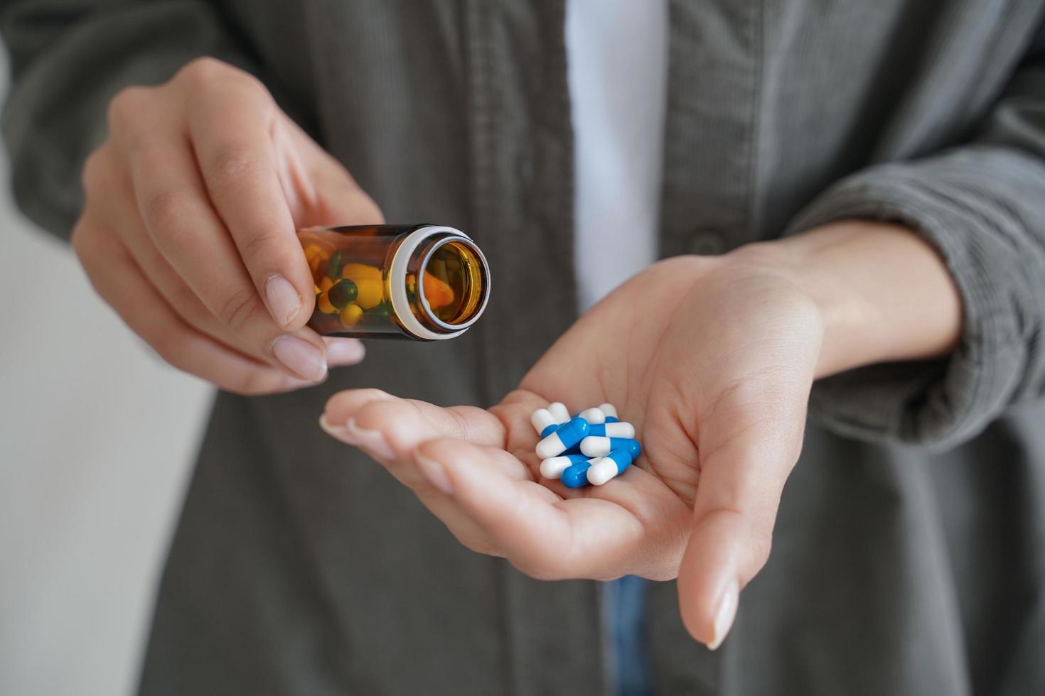 Female holding pills takes medicine, painkiller, vitamins, oral contraceptives or dietary supplement photo