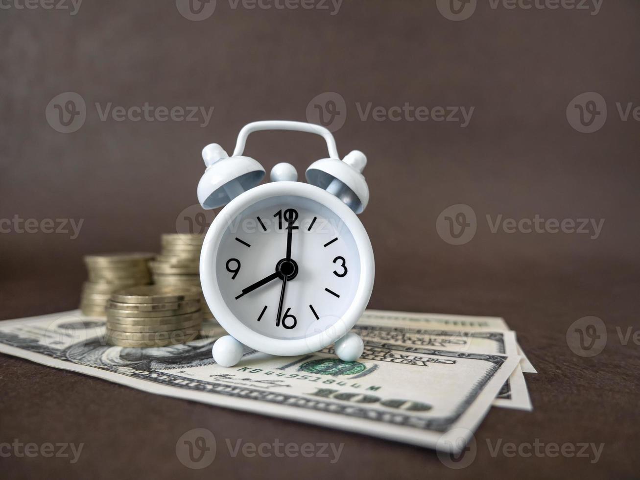 Alarm clock, coins and banknotes on a dark background. The idea of business, Finance concept and saving money and time photo