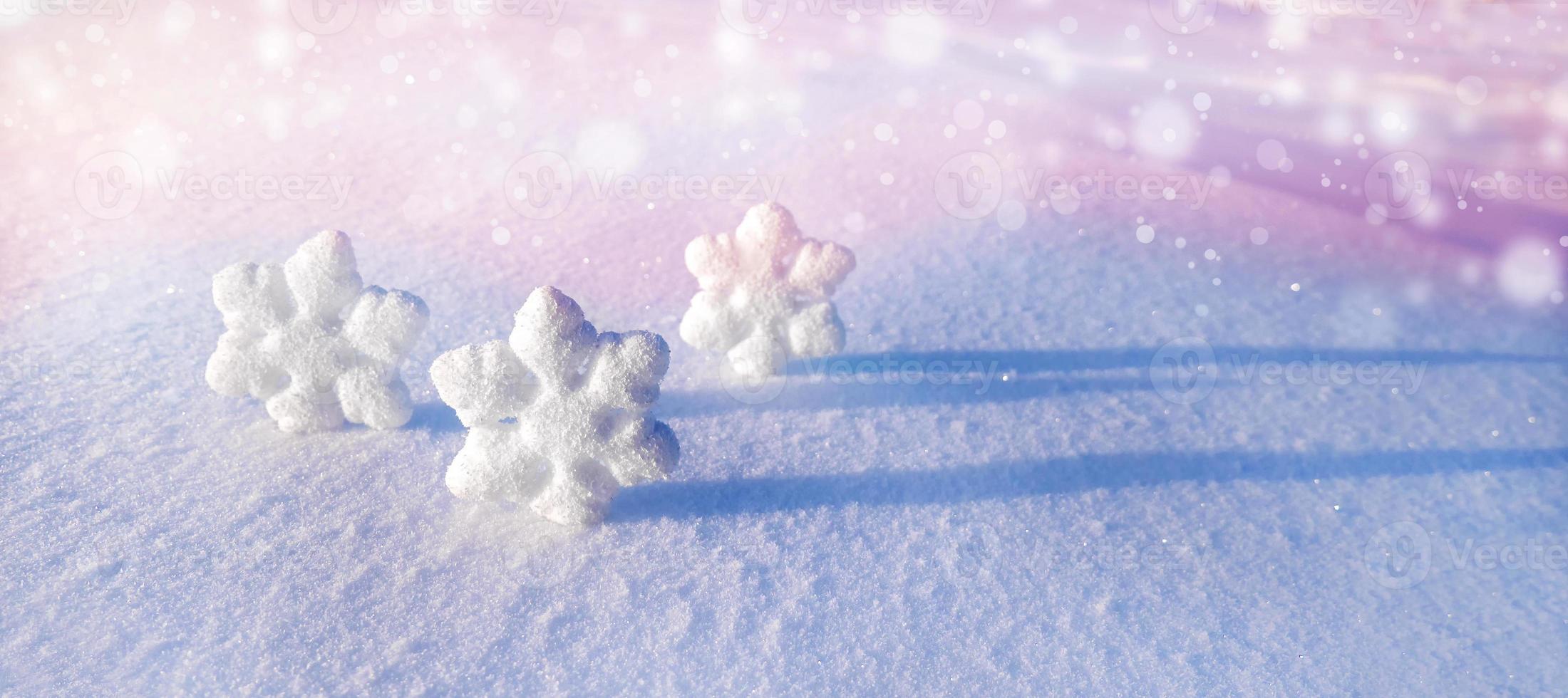 Christmas snowflakes on white snow on a frosty sunny winter day. Abstract defocused background with bokeh. Banner ad photo