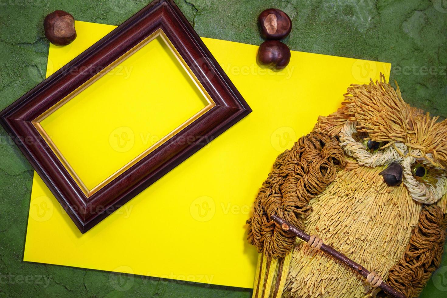 Yellow paper with owl and frame, chestnuts on green background. Place for text. Copy space photo