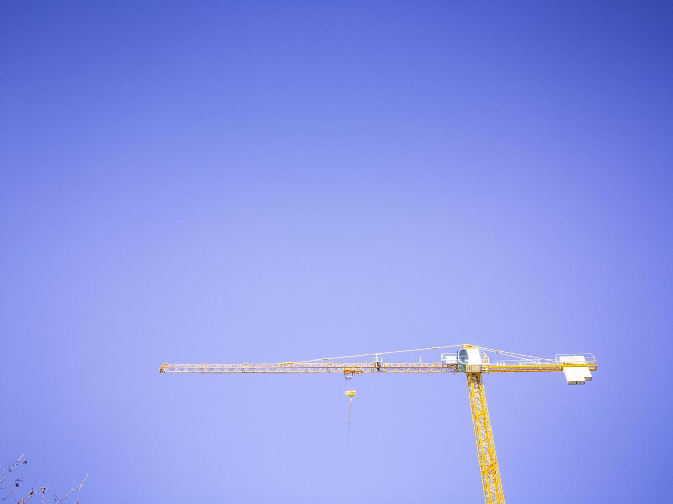 Isolated yellow construction crane in blue sky background photo