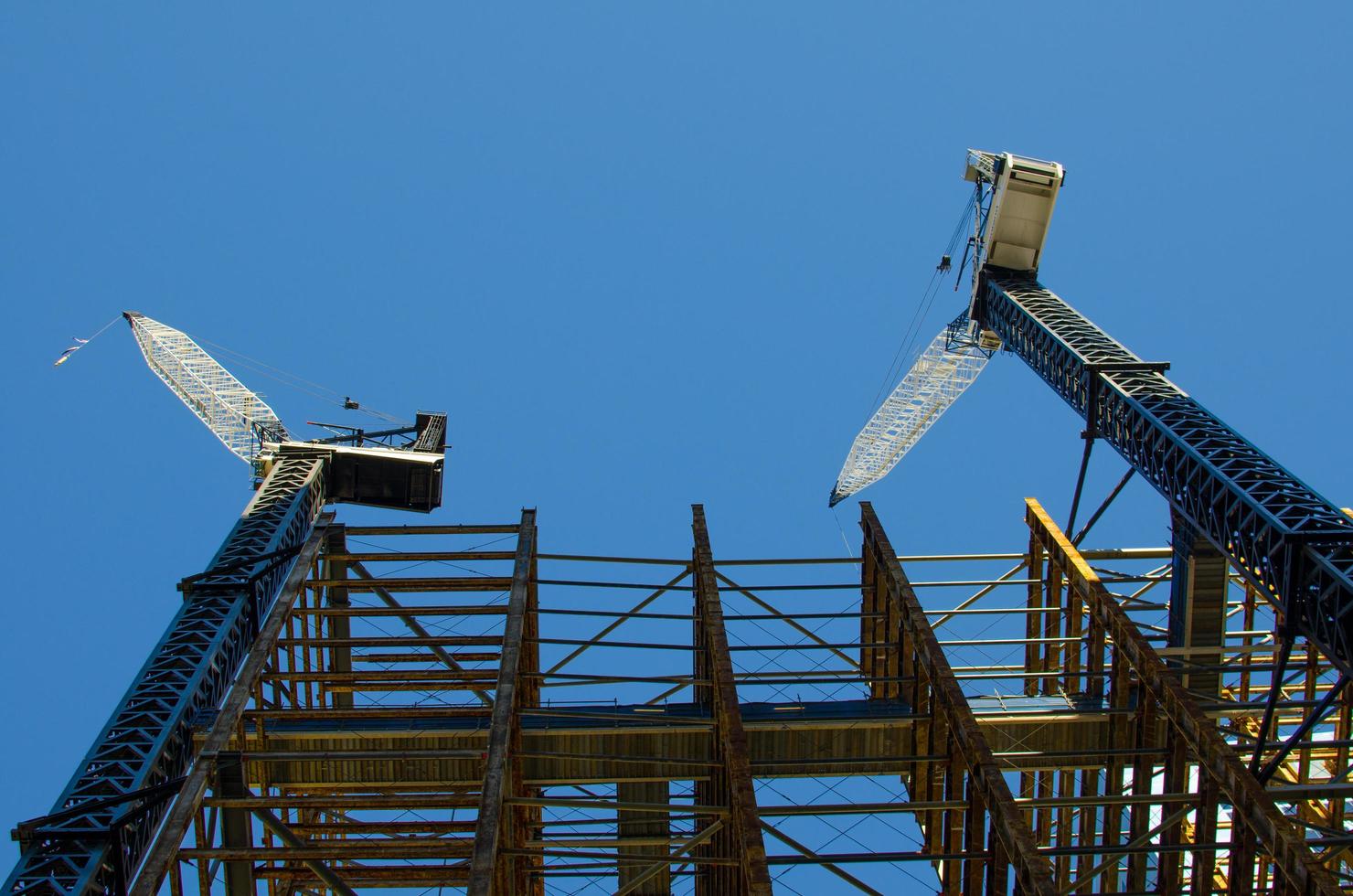 dos grúas de construcción en el sitio de construcción con fondo de cielo azul. foto