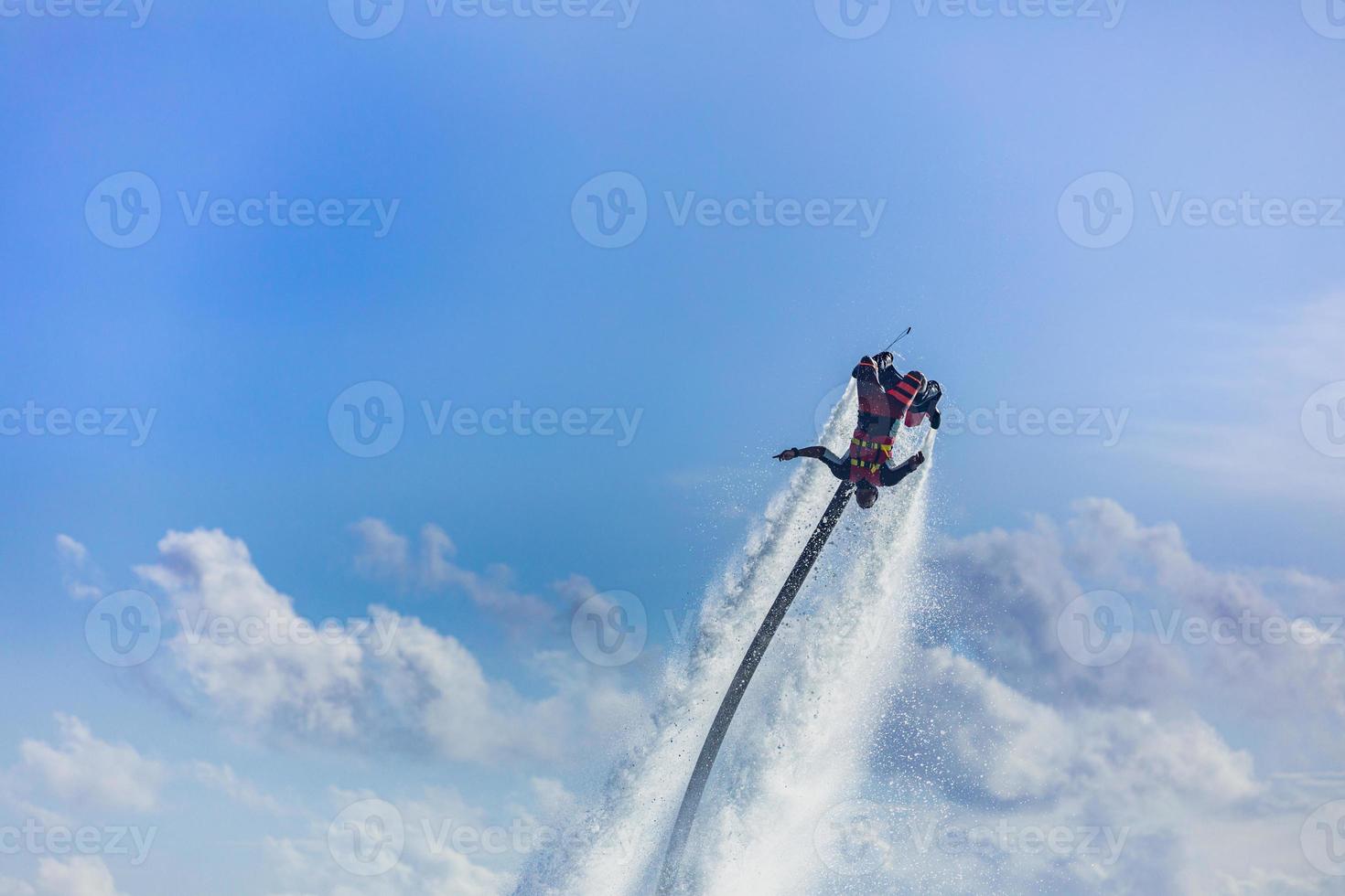 island sunset. Professional fly board rider doing back flip with tropical resort island background. Sunset sport and summer activity background, fun water sport photo