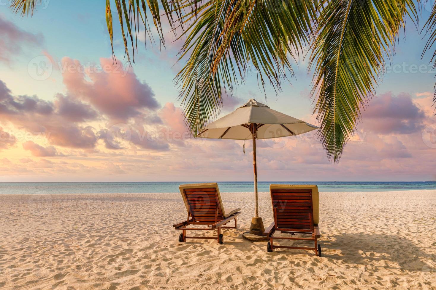 increíble puesta de sol en la playa. sombrilla de sillas de pareja romántica. tranquilidad unión amor concepto paisaje, playa relax, hermoso diseño paisajístico. escapada a la costa de la isla tropical, hojas de palma, idílica vista al mar foto