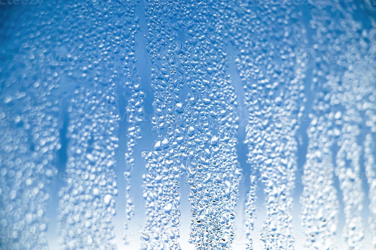 Texture of misted glass in winter. Frozen drops of water in sun on window. photo