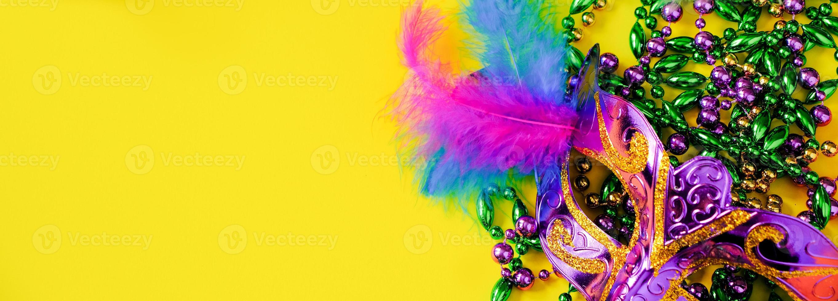 Carnival mask with feathers on yellow background. Multicolored beads Mardi Gras or Fat Tuesday symbol. photo