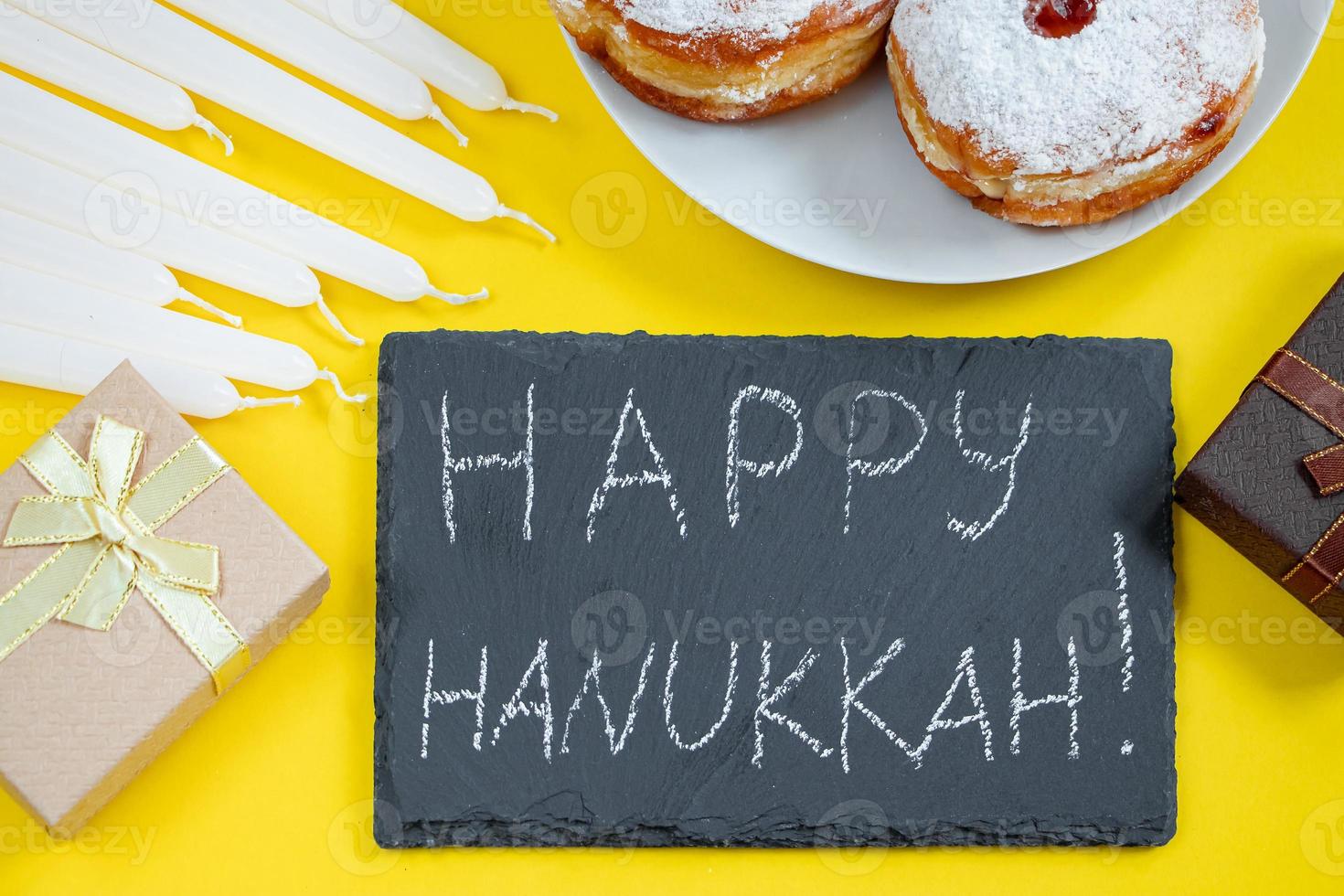 Happy Hanukkah. Jewish dessert Sufganiyot on yellow background. Symbols of religious Judaism holiday. Donuts, candles and gift. photo