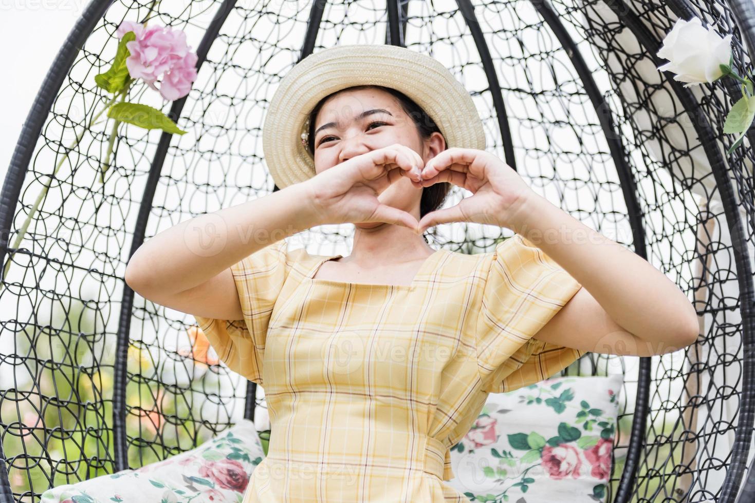 una hermosa mujer asiática haciendo el signo de la mano del corazón al aire libre. foto