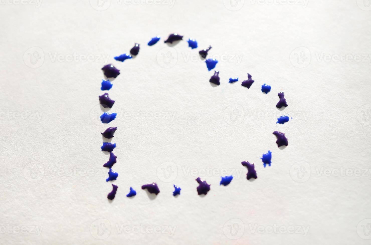 Image of a heart made from wet drops of watercolor paint on a paper sheet photo