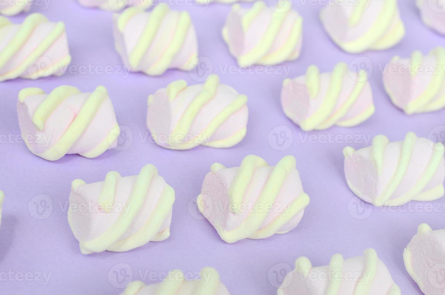 Colorful marshmallow laid out on violet paper background. pastel creative textured pattern. Perspective macro shot photo
