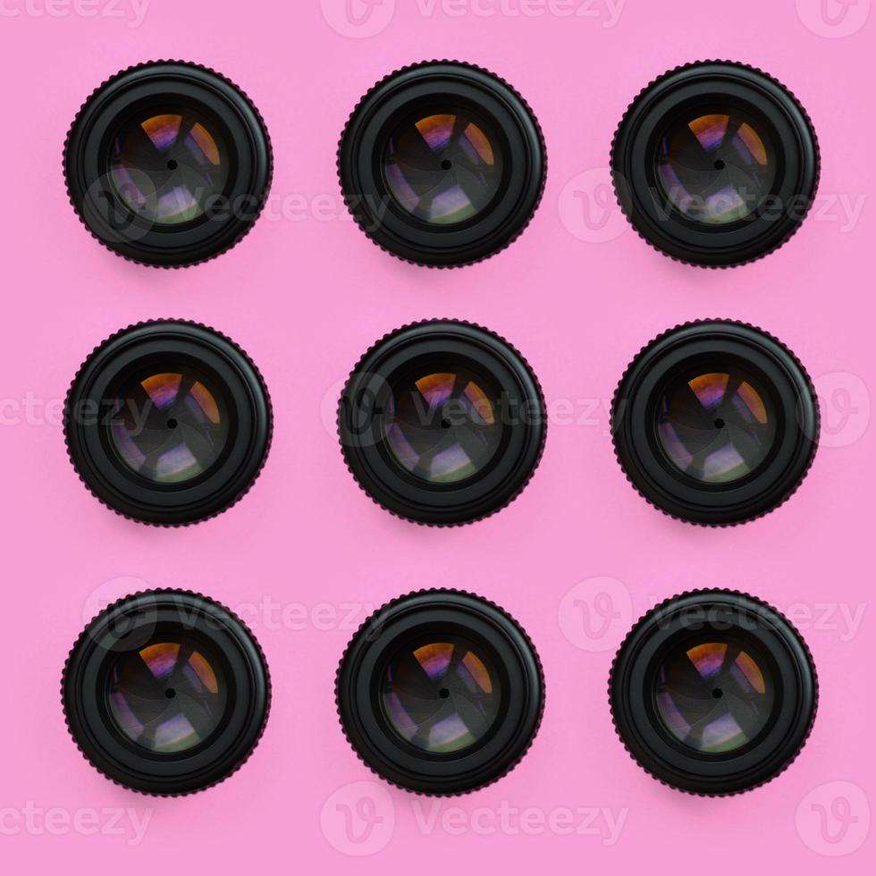 A few camera lenses with a closed aperture lie on texture background of fashion pastel pink color paper in minimal concept. Abstract trendy pattern photo