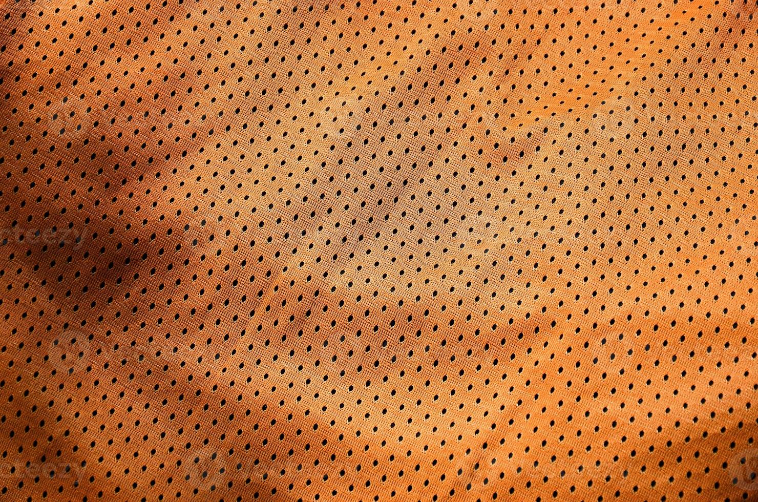 Fondo de textura de tela de ropa deportiva. vista superior de la superficie textil de tela de nailon de poliéster naranja. camiseta de baloncesto de color con espacio libre para texto foto