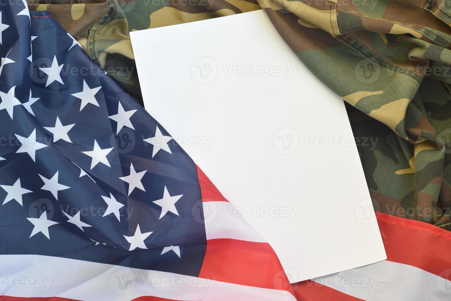 Blank paper lies on United States of America flag and folded military uniform jacket. Military symbols conceptual background banner and copy space photo