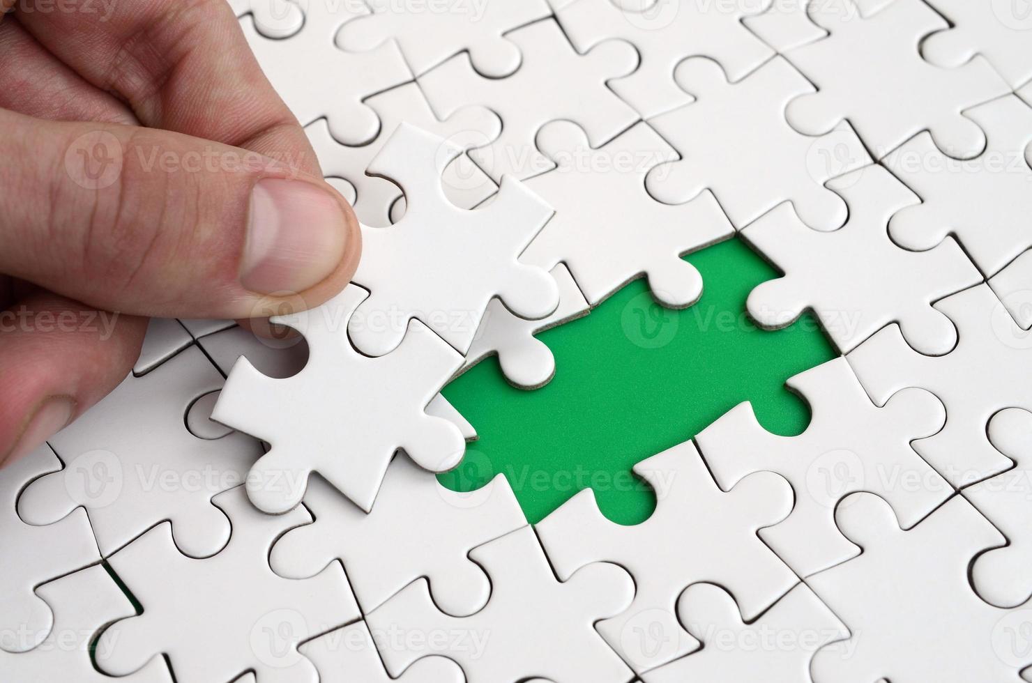 The human hand fills the last missing elements of the surface from the jigsaw puzzle. The concept of the completion of the initiated cases photo