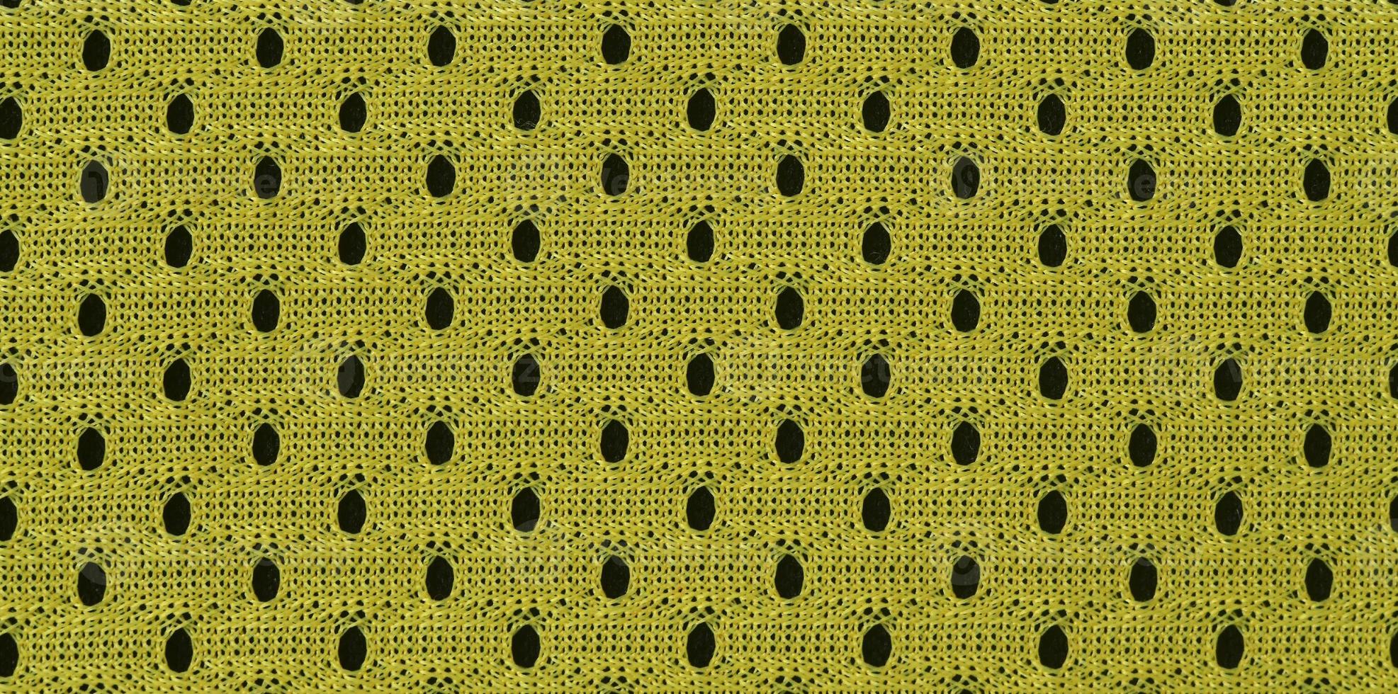 Background image of a fabric texture of a yellow jersey made of polyester nylon. Macro photo with shallow depth of field