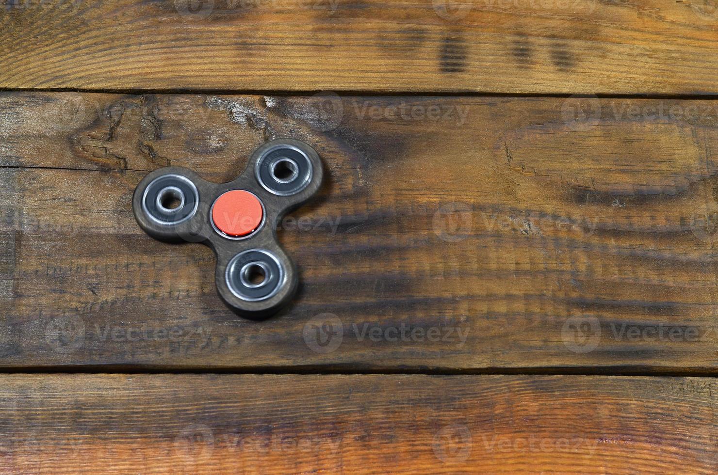 A rare handmade wooden fidget spinner lies on a brown wooden background surface. Trendy stress relieving toy photo