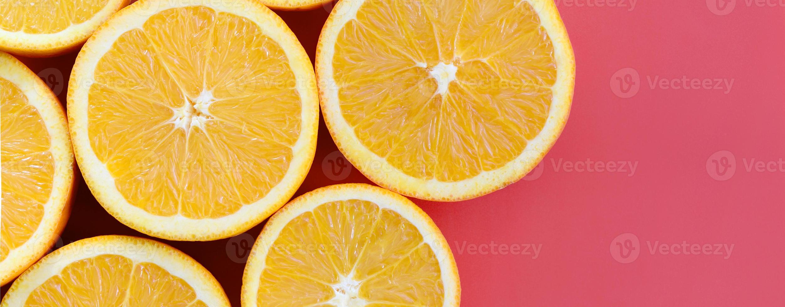 Top view of a several orange fruit slices on bright background in red color. A saturated citrus texture image photo
