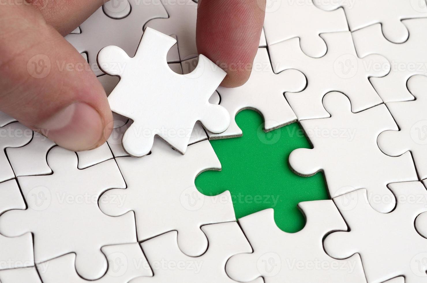 The human hand fills the last missing elements of the surface from the jigsaw puzzle. The concept of the completion of the initiated cases photo