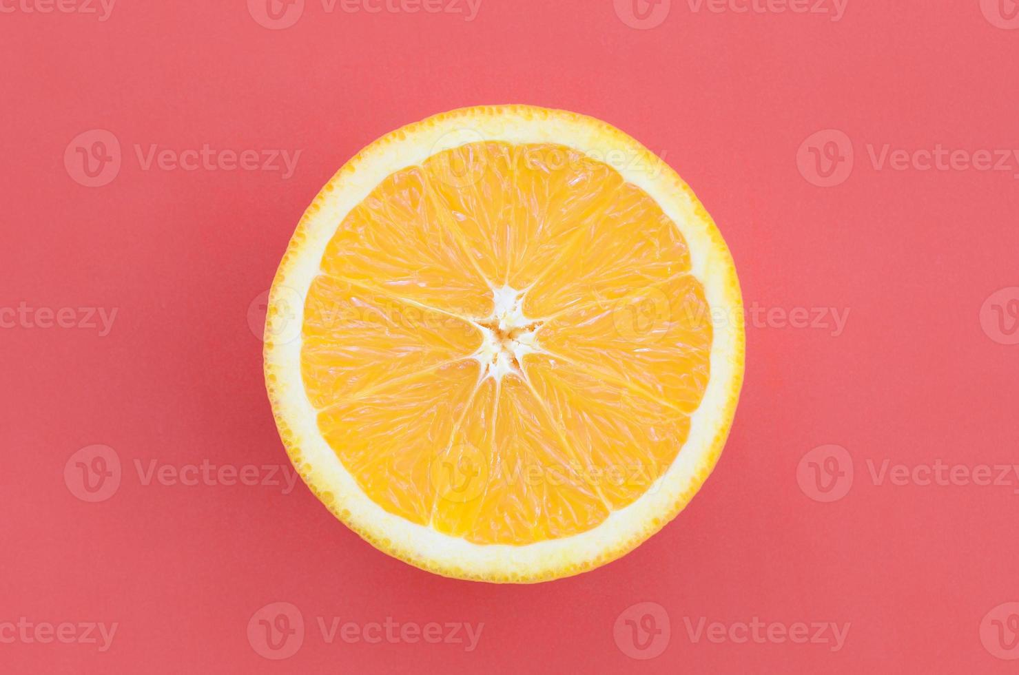 Top view of a one orange fruit slice on bright background in red color. A saturated citrus texture image photo