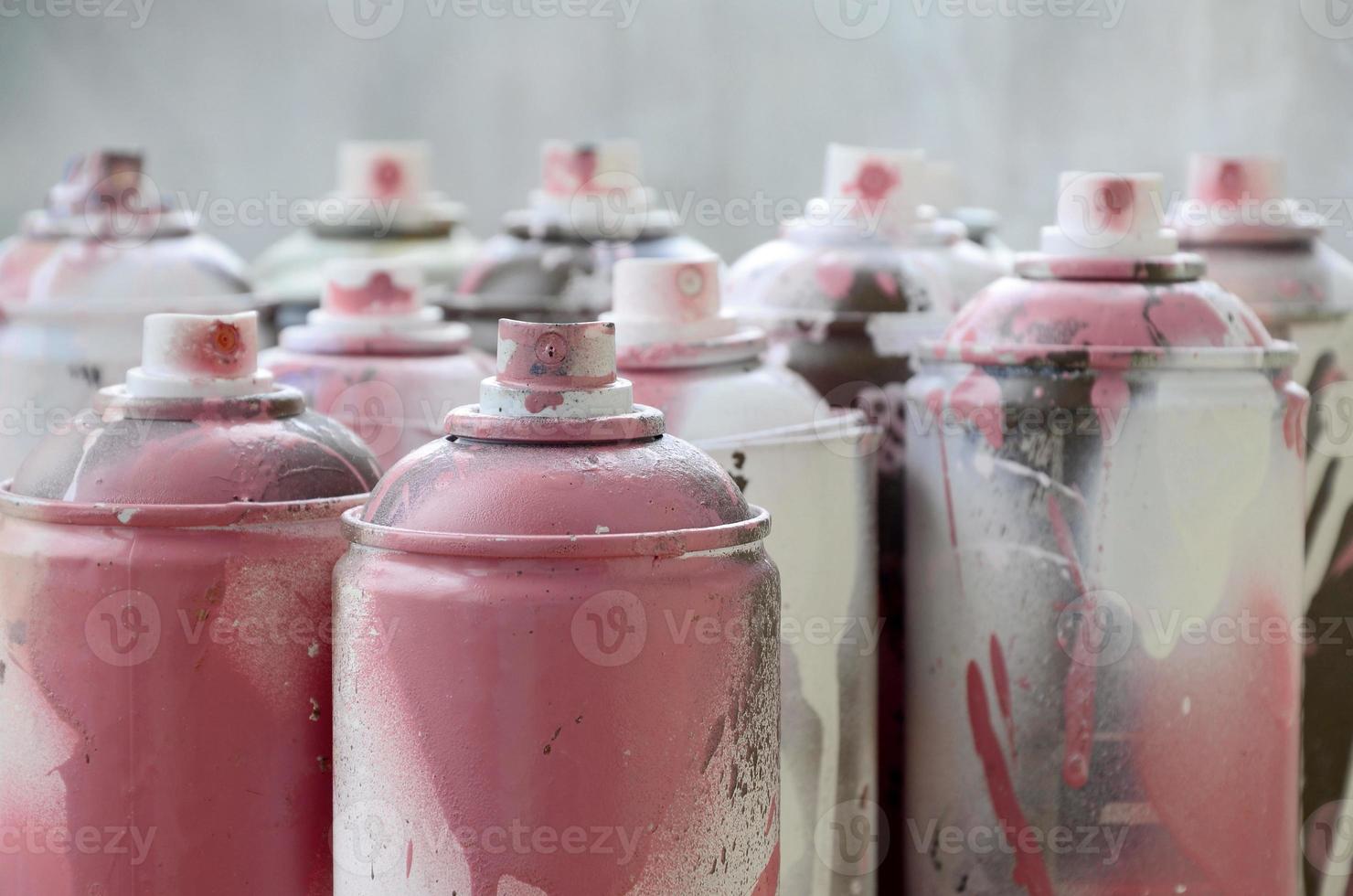 A lot of dirty and used aerosol cans of bright pink paint. Macro photograph with shallow depth of field. Selective focus on the spray nozzle photo