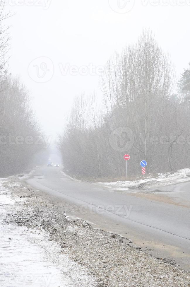 Crossroads on a suburban asphalt road in wintertime during a blizzard photo