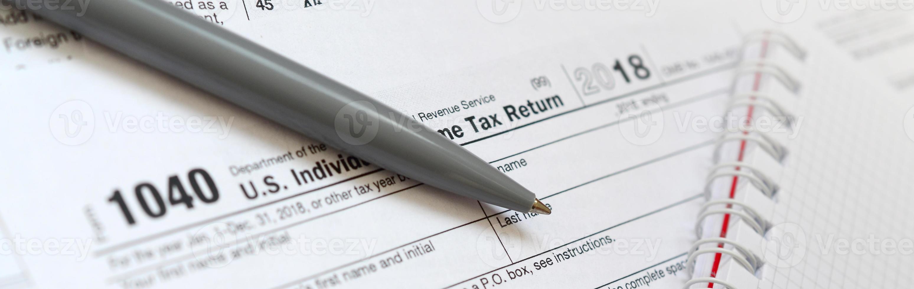 el bolígrafo y el cuaderno se encuentran en el formulario de impuestos 1040 us declaración de impuestos sobre la renta individual. la hora de pagar impuestos foto