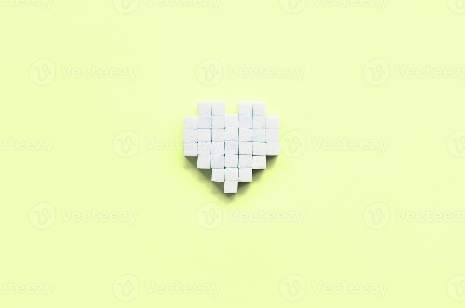 A heart made of sugar cubes lies on a trendy pastel lime photo