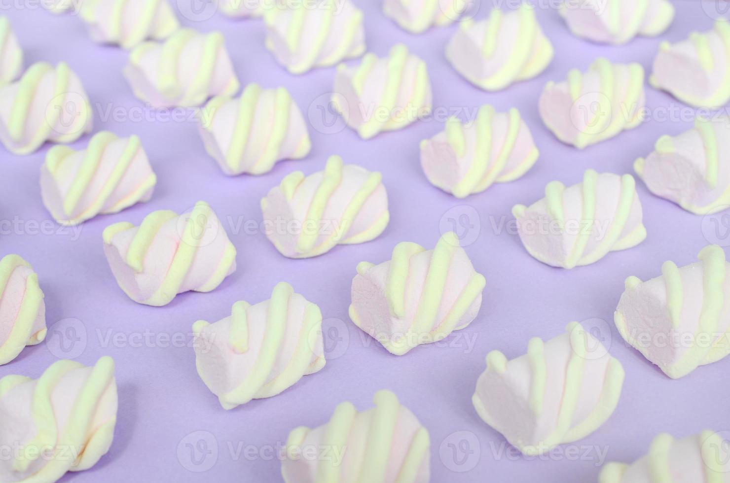 Colorful marshmallow laid out on violet paper background. pastel creative textured pattern. Perspective macro shot photo