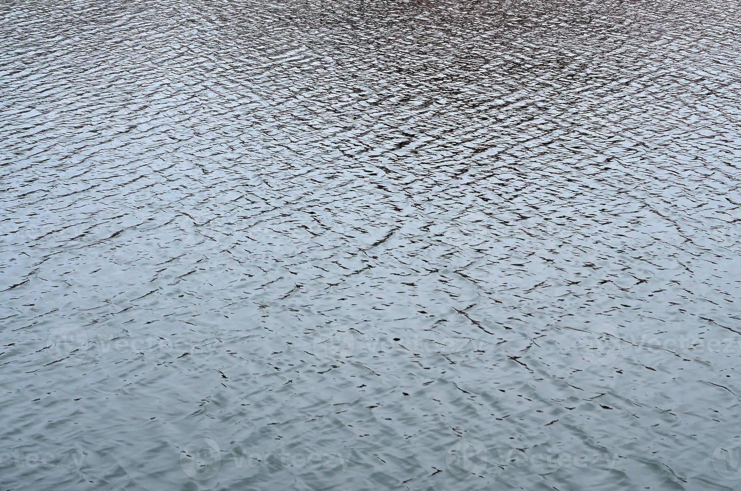 la textura del agua en el río bajo la influencia del viento. muchas olas poco profundas en la superficie del agua foto
